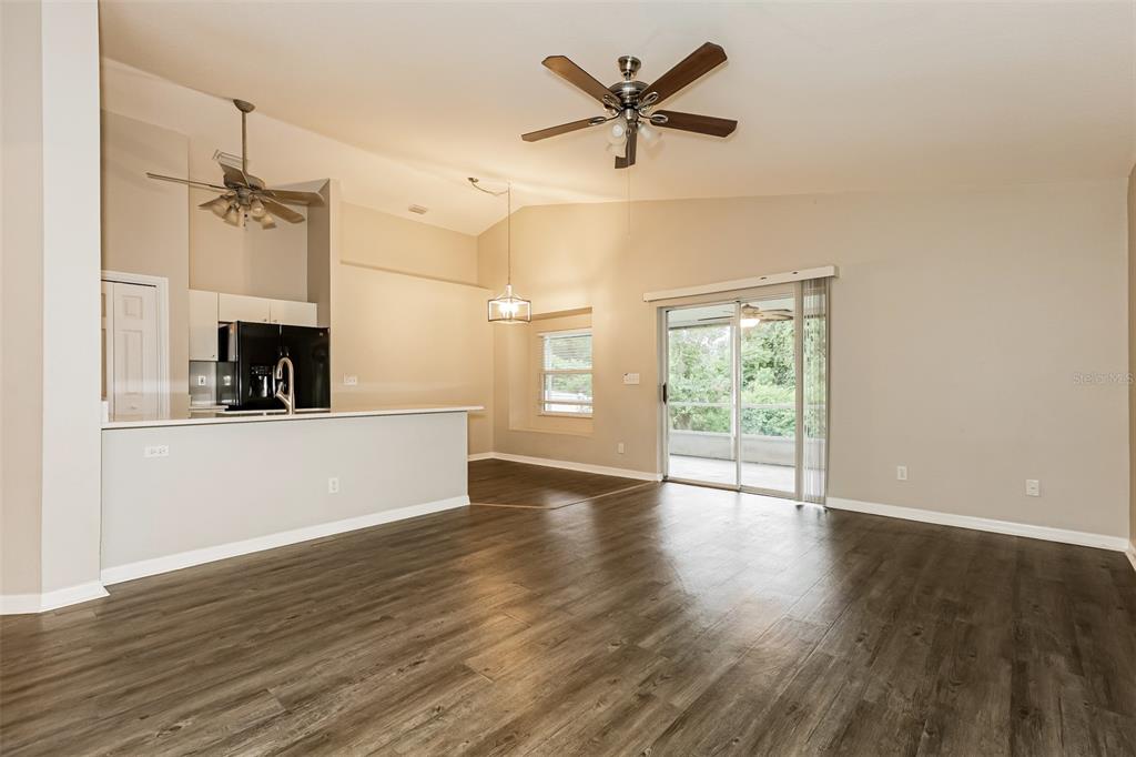 An open-concept living area features wood-look flooring, a kitchen island, and a sliding glass door — 823 ROCKY MOUNTAIN COURT, VALRICO, FL