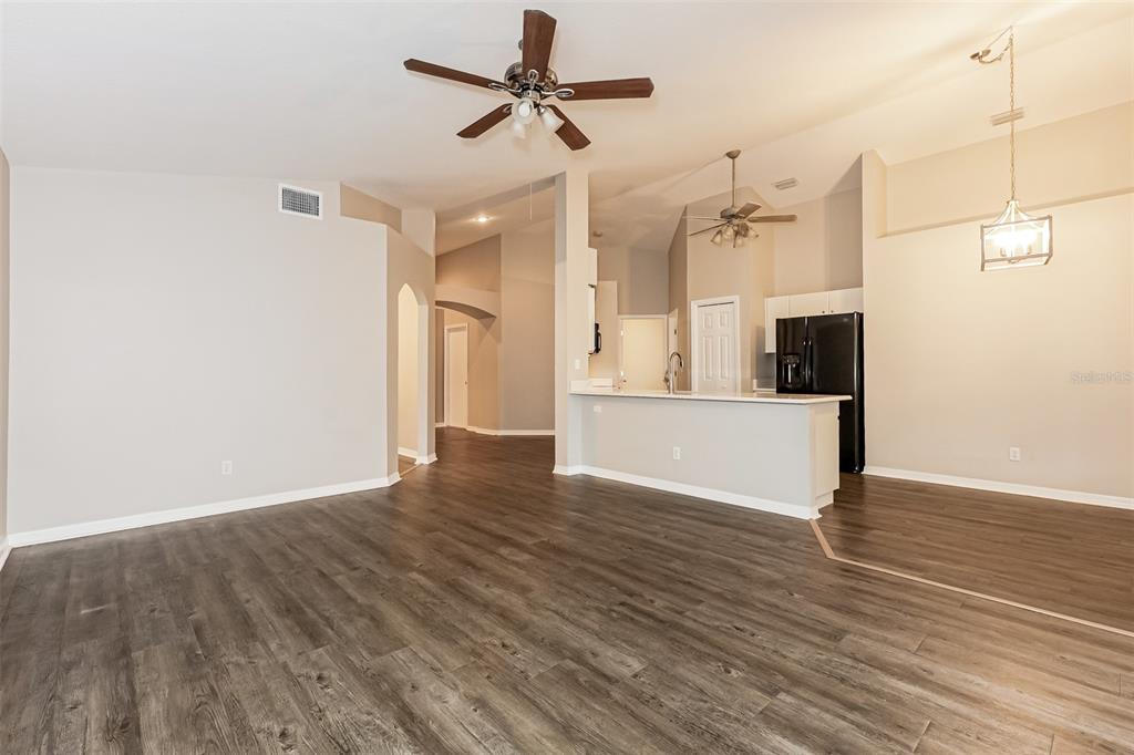 An open-concept living and dining area features wood-look flooring, a kitchen island, and ceiling fans — 823 ROCKY MOUNTAIN COURT, VALRICO, FL