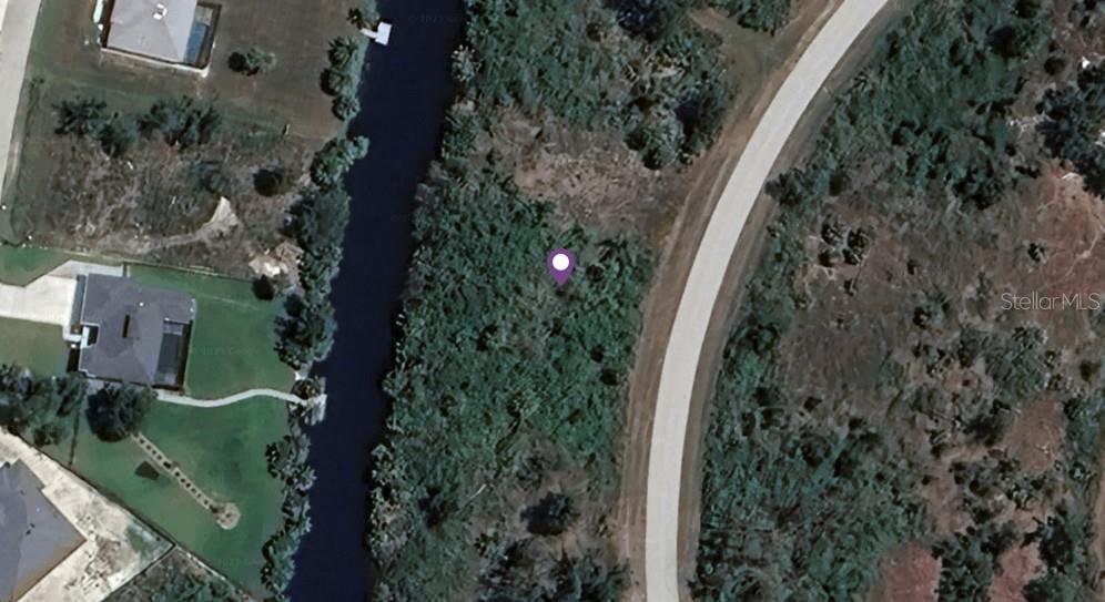 This aerial map shows a vacant, wooded lot situated between a canal and a road — 7529 PINEDALE DRIVE, PORT CHARLOTTE, FL