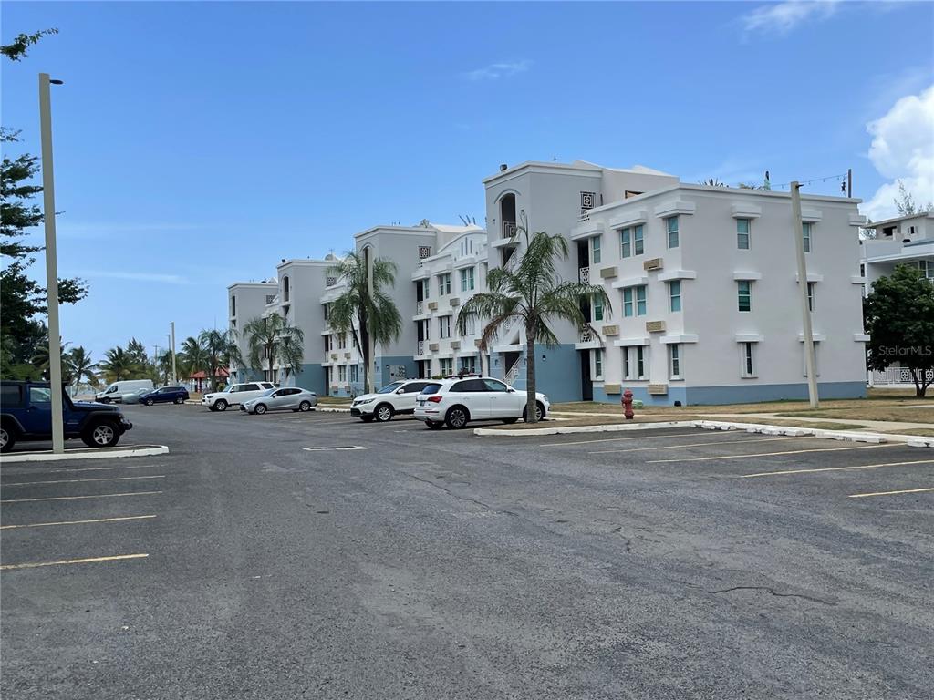 A multi-story apartment building with a parking lot in the foreground under a blue sky — II LOS PARILLAS UNIT 3501, LOIZA, PR