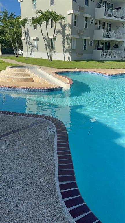 A swimming pool with a small slide sits in front of a multi-story apartment building — II LOS PARILLAS UNIT 3501, LOIZA, PR