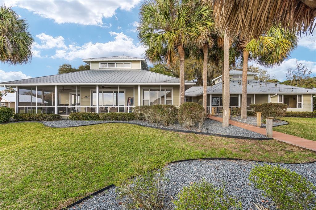 A single-story house with a metal roof, screened porch, and palm trees in the yard — 14261 SE 128TH STREET, OCKLAWAHA, FL