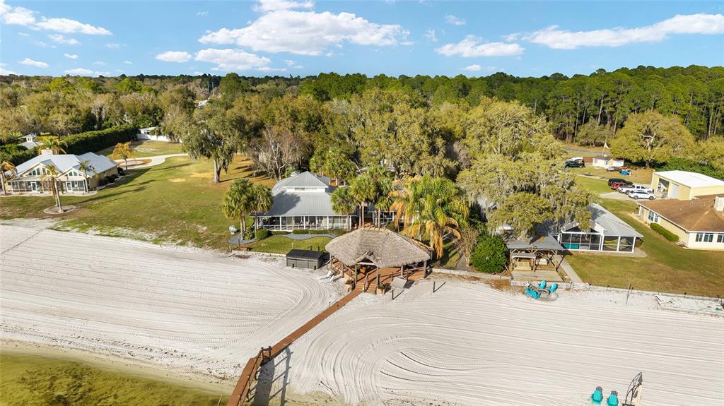 An aerial view shows a waterfront property with a sandy beach, dock, and multiple buildings — 14261 SE 128TH STREET, OCKLAWAHA, FL