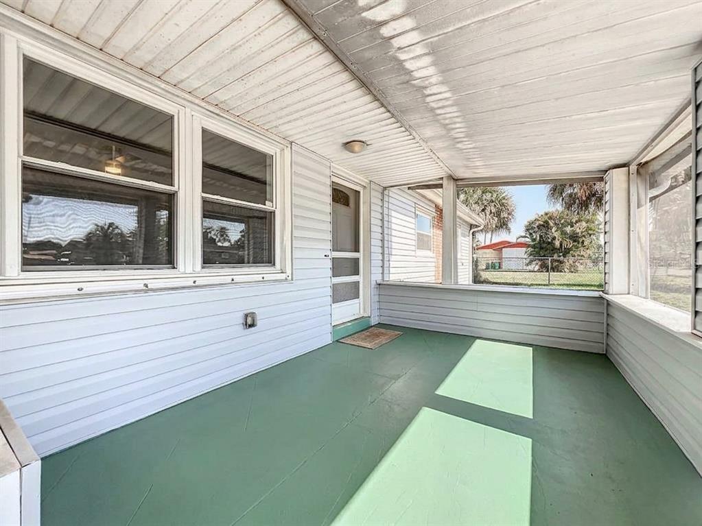 A covered porch with light blue siding, a green floor, and large windows — 2543 HATHAWAY DRIVE, COCOA, FL