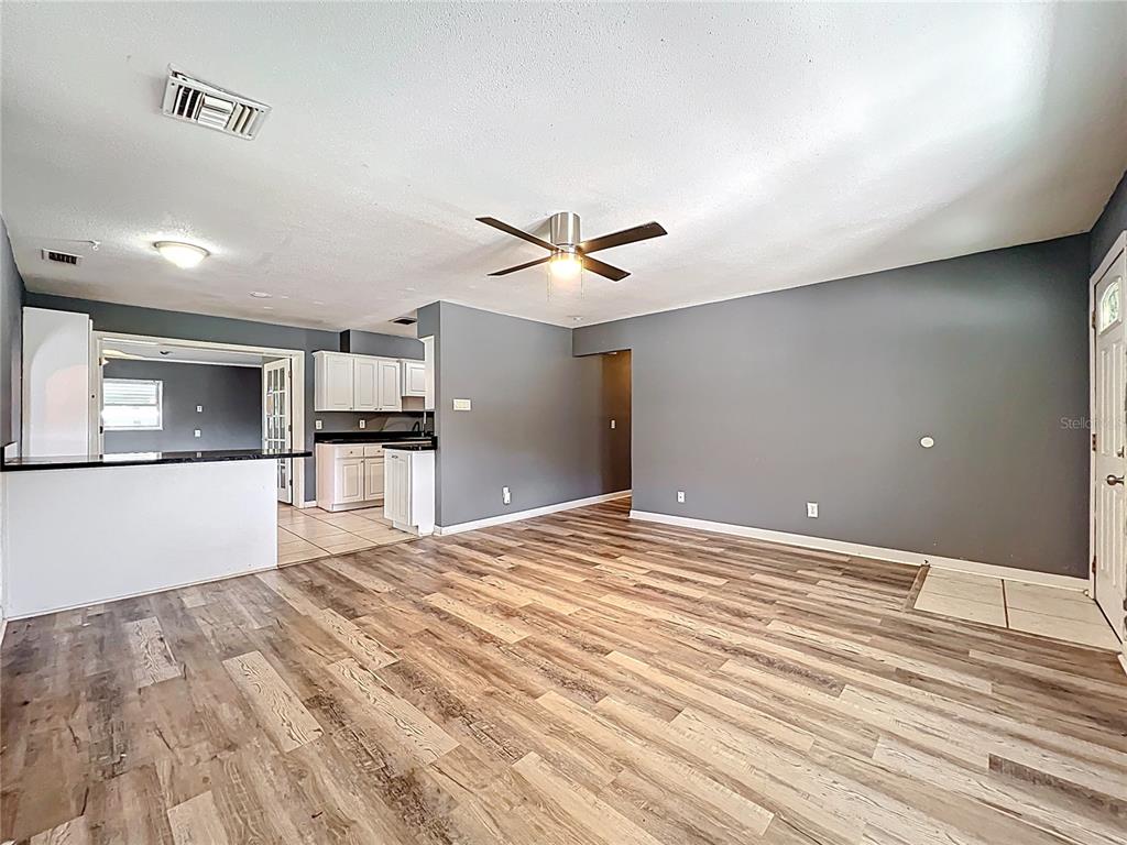 An open-concept living area features wood-look flooring, gray walls, and an adjacent white kitchen — 2543 HATHAWAY DRIVE, COCOA, FL
