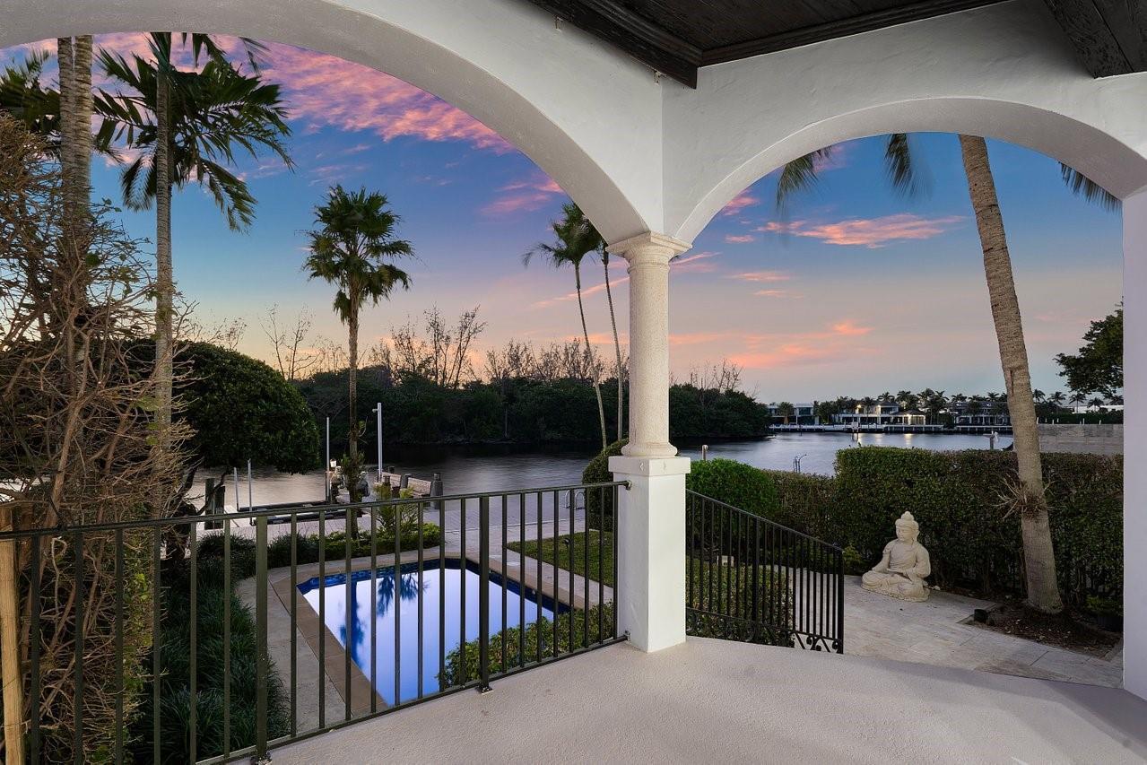 A covered patio overlooks a small pool, a metal fence, and a canal at sunset — 549 NE 19th Avenue # C, Deerfield Beach FL 33441, DEERFIELD BEACH, FL