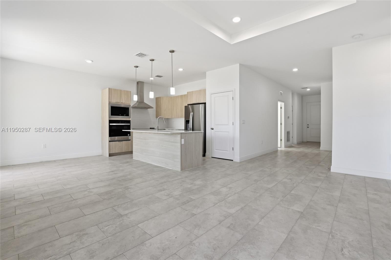 A modern kitchen features light wood cabinets, stainless steel appliances, and a central island — 1087 Rugby Ln, La Belle FL 33935, LA BELLE, FL