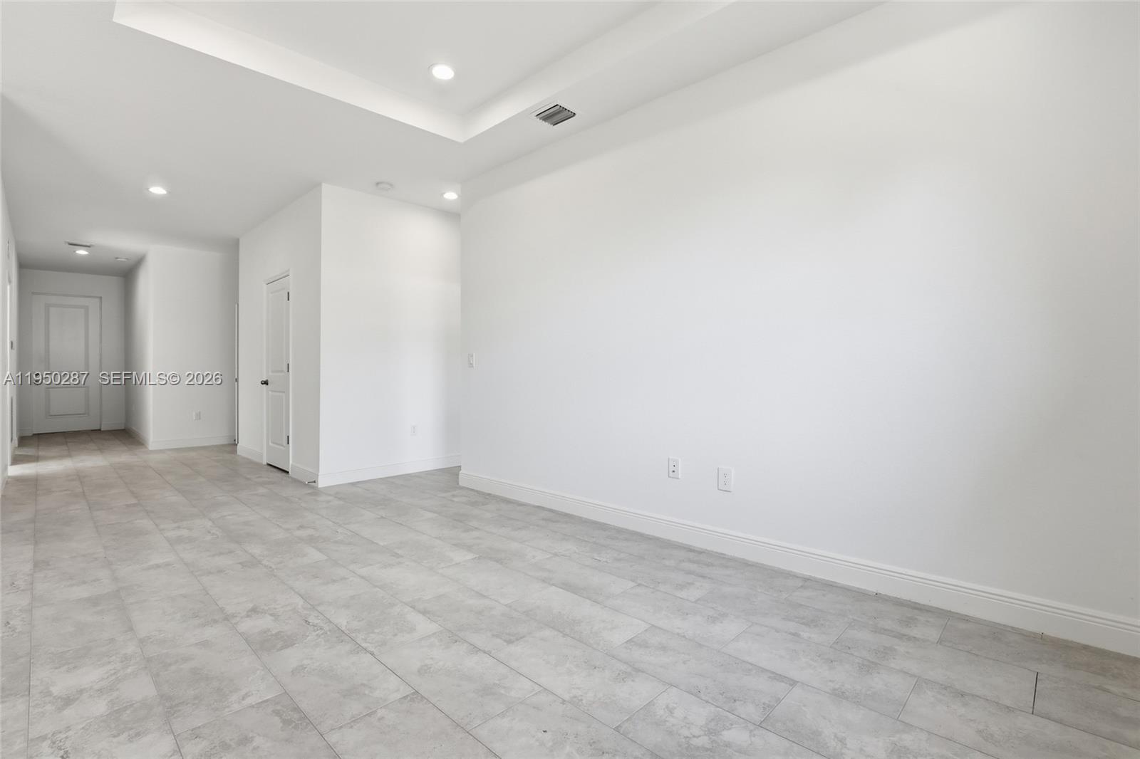 A minimalist room features white walls, a tray ceiling, and light gray tile flooring — 1087 Rugby Ln, La Belle FL 33935, LA BELLE, FL