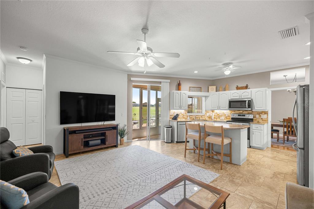 An open-concept living room and kitchen featuring white cabinets, a center island, and tile flooring — 2081 NW 58TH COURT, OCALA, FL