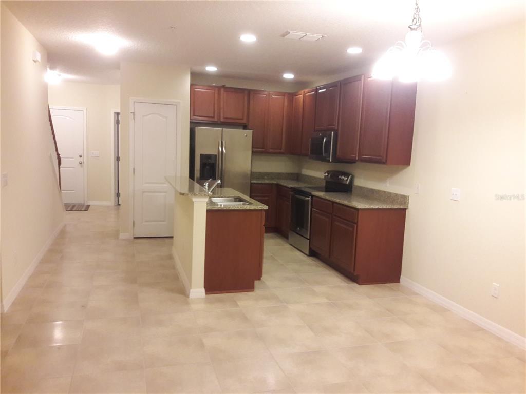 A kitchen features dark wood cabinets, granite countertops, stainless steel appliances, and tile flooring — 2318 ALOHA BAY COURT, OCOEE, FL