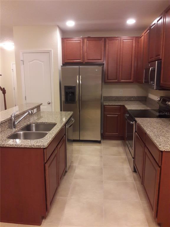 A kitchen features wood cabinets, granite countertops, stainless steel appliances, and a double-basin sink — 2318 ALOHA BAY COURT, OCOEE, FL