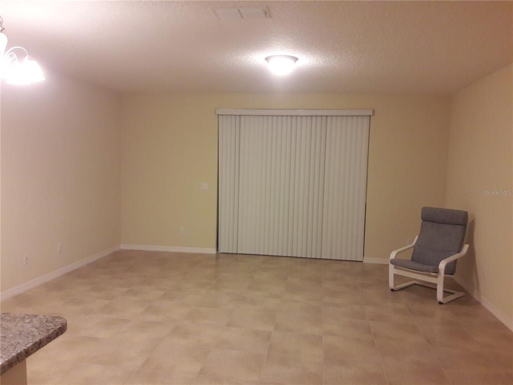 A spacious room with light-colored tile flooring, beige walls, and a sliding glass door — 2318 ALOHA BAY COURT, OCOEE, FL