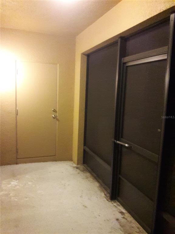 A concrete patio features a solid door and a dark-framed screened door — 2318 ALOHA BAY COURT, OCOEE, FL