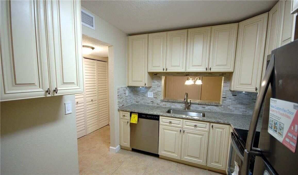 A kitchen features cream-colored cabinets, granite countertops, stainless steel appliances, and a tiled backsplash — 3071 Holiday Springs Boulevard # 101, Margate FL 33063, MARGATE, FL