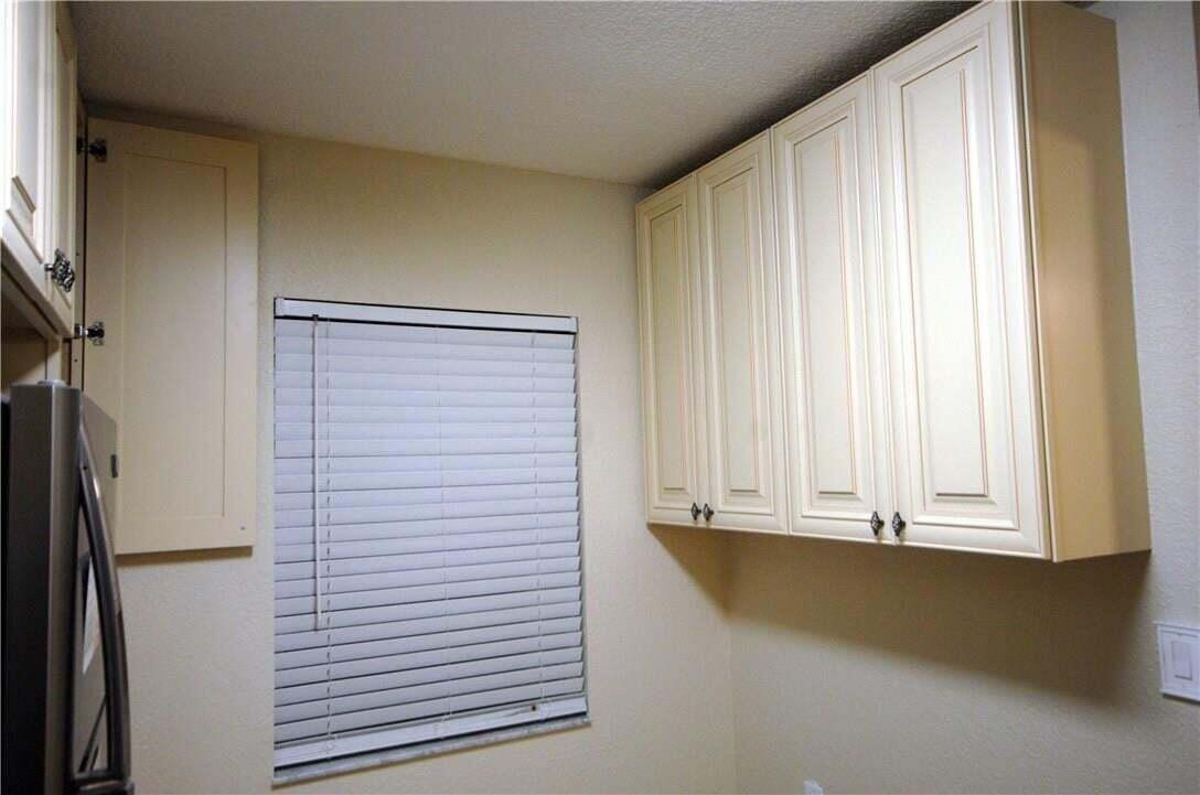 A kitchen wall features cream-colored cabinets, a window with white blinds, and a stainless refrigerator — 3071 Holiday Springs Boulevard # 101, Margate FL 33063, MARGATE, FL