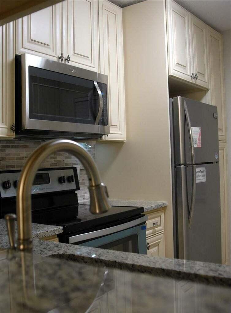 A kitchen featuring stainless steel appliances, cream-colored cabinets, and granite countertops — 3071 Holiday Springs Boulevard # 101, Margate FL 33063, MARGATE, FL