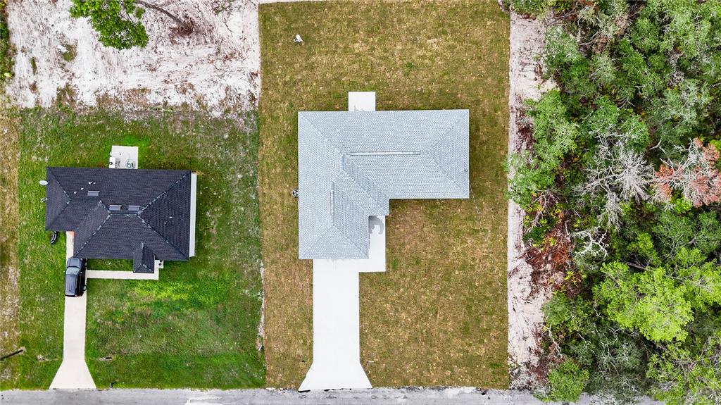 An aerial view shows two houses with driveways situated on adjacent lots next to a forest — 11 MALAUKA PASS, OCKLAWAHA, FL
