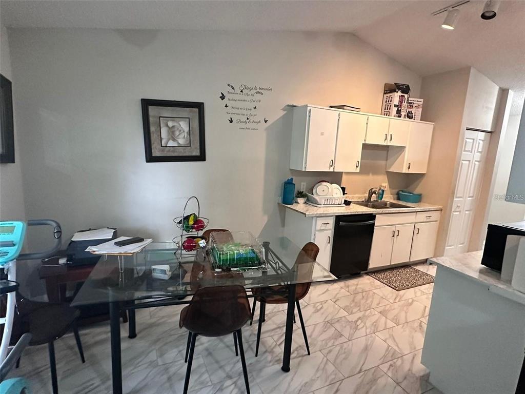 A dining area with a glass table and chairs sits adjacent to a small kitchen — 1021 EMBRUN COURT, KISSIMMEE, FL
