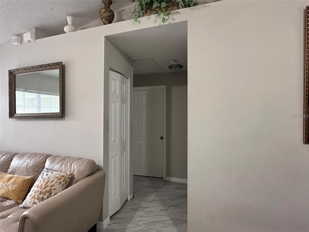 A living room features a beige sofa, a wall mirror, and a tiled hallway entrance — 1021 EMBRUN COURT, KISSIMMEE, FL