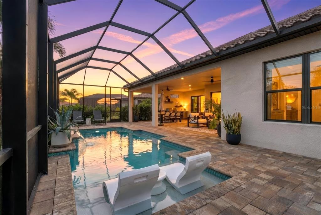 A screened-in patio features a swimming pool with lounge chairs and a covered seating area — 10003 BATCHELDER TERRACE, PALMETTO, FL