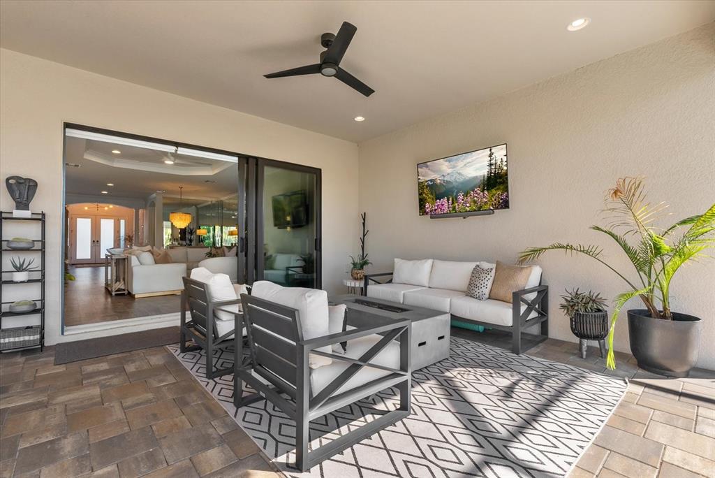 A covered outdoor patio features a seating area, a wall-mounted television, and a ceiling fan — 10003 BATCHELDER TERRACE, PALMETTO, FL