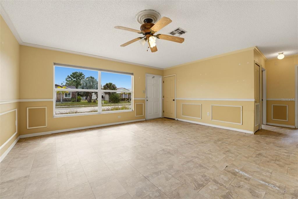 A living room with yellow walls, white wainscoting, tile flooring, and a ceiling fan — 6399 CONISTON STREET, PORT CHARLOTTE, FL