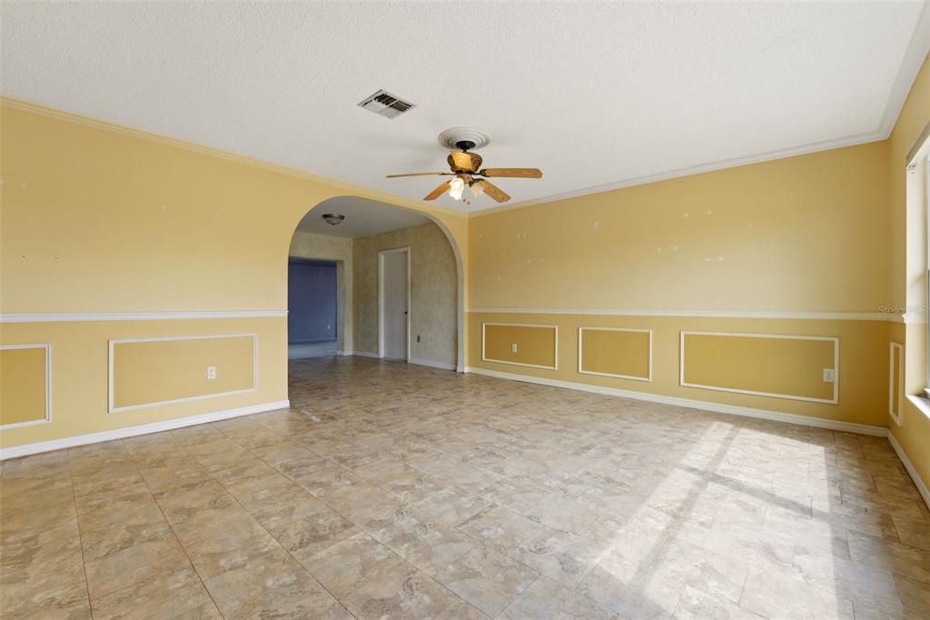 A living room with yellow walls, white wainscoting, tile flooring, and an arched doorway — 6399 CONISTON STREET, PORT CHARLOTTE, FL