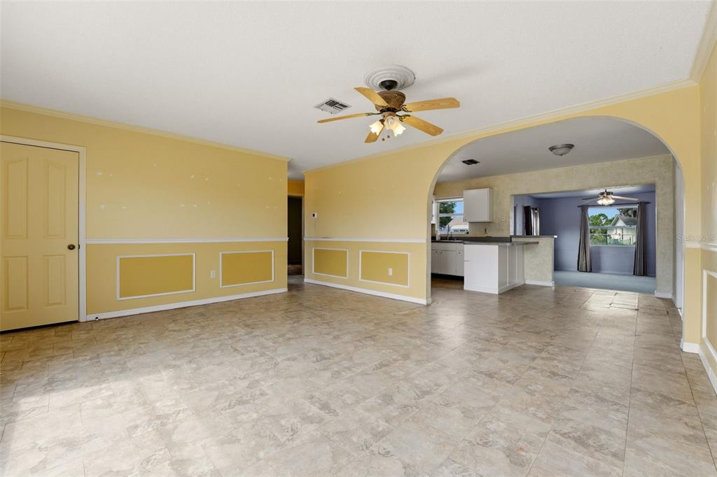 A living room with yellow walls, wainscoting, and tile flooring leads into a kitchen area — 6399 CONISTON STREET, PORT CHARLOTTE, FL