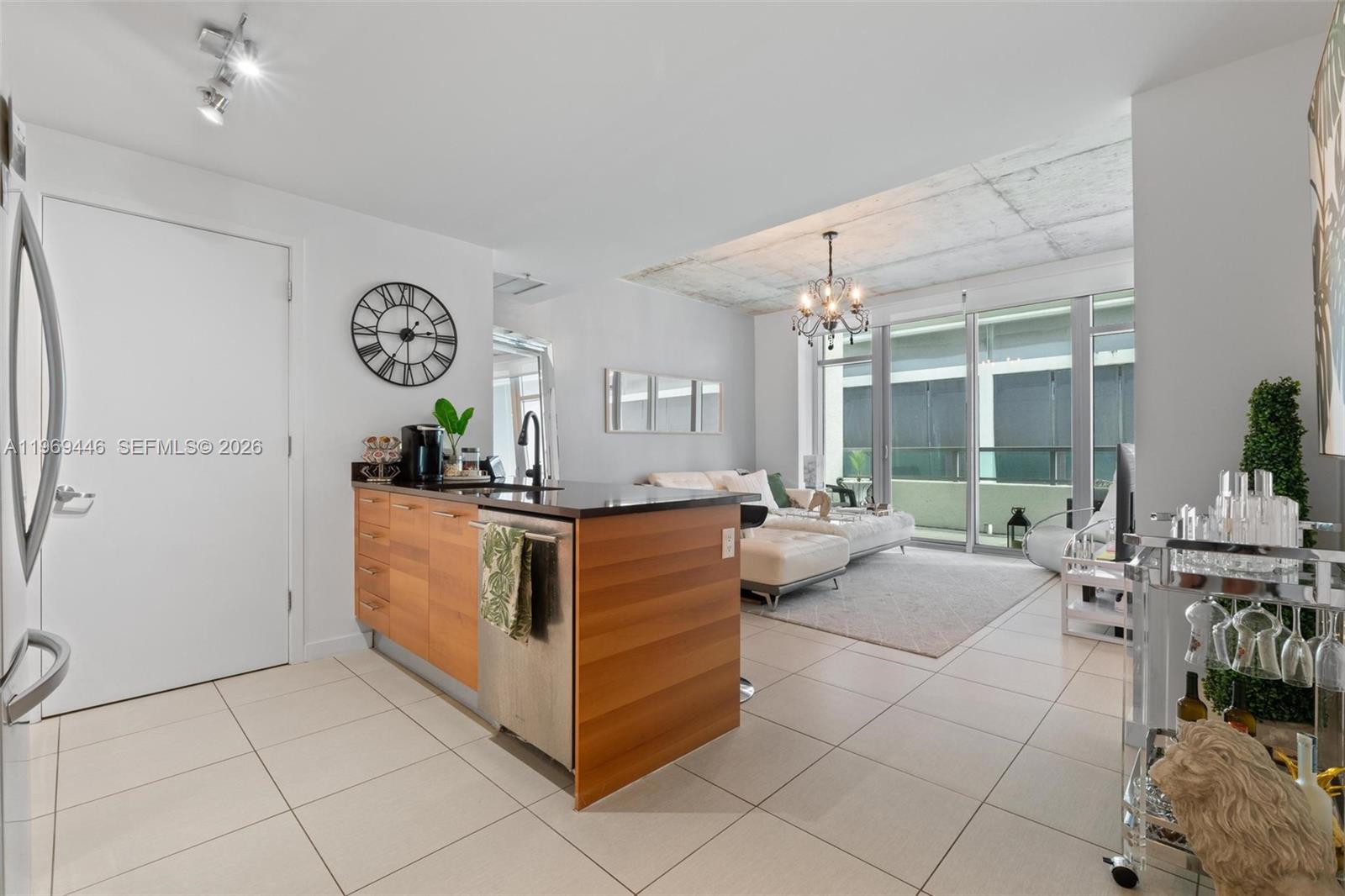 A modern kitchen island with wood cabinetry faces a living area with a concrete ceiling — 3301 NE 1st Ave # L0304, Miami FL 33137, MIAMI, FL