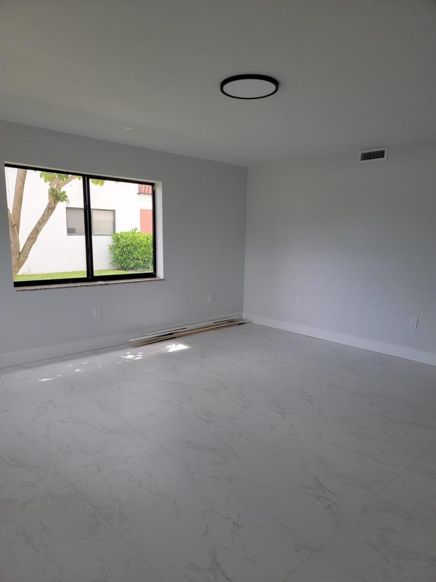An empty room with light gray walls, white marble-look tile flooring, and a large window — 240 SW 7th Street # 9, Boca Raton FL 33432, BOCA RATON, FL