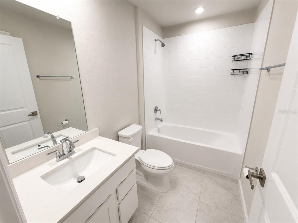 A bathroom features a white vanity, a toilet, and a shower-tub combination with white tile — 4213 CATTAIL MARSH DRIVE, LAKELAND, FL