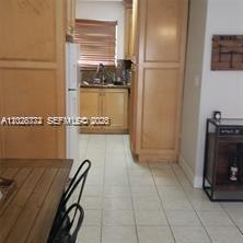 A kitchen with light wood cabinets, tile flooring, and a dining area in the foreground — 8089 NW 8th St # 3, Miami FL 33126, MIAMI, FL