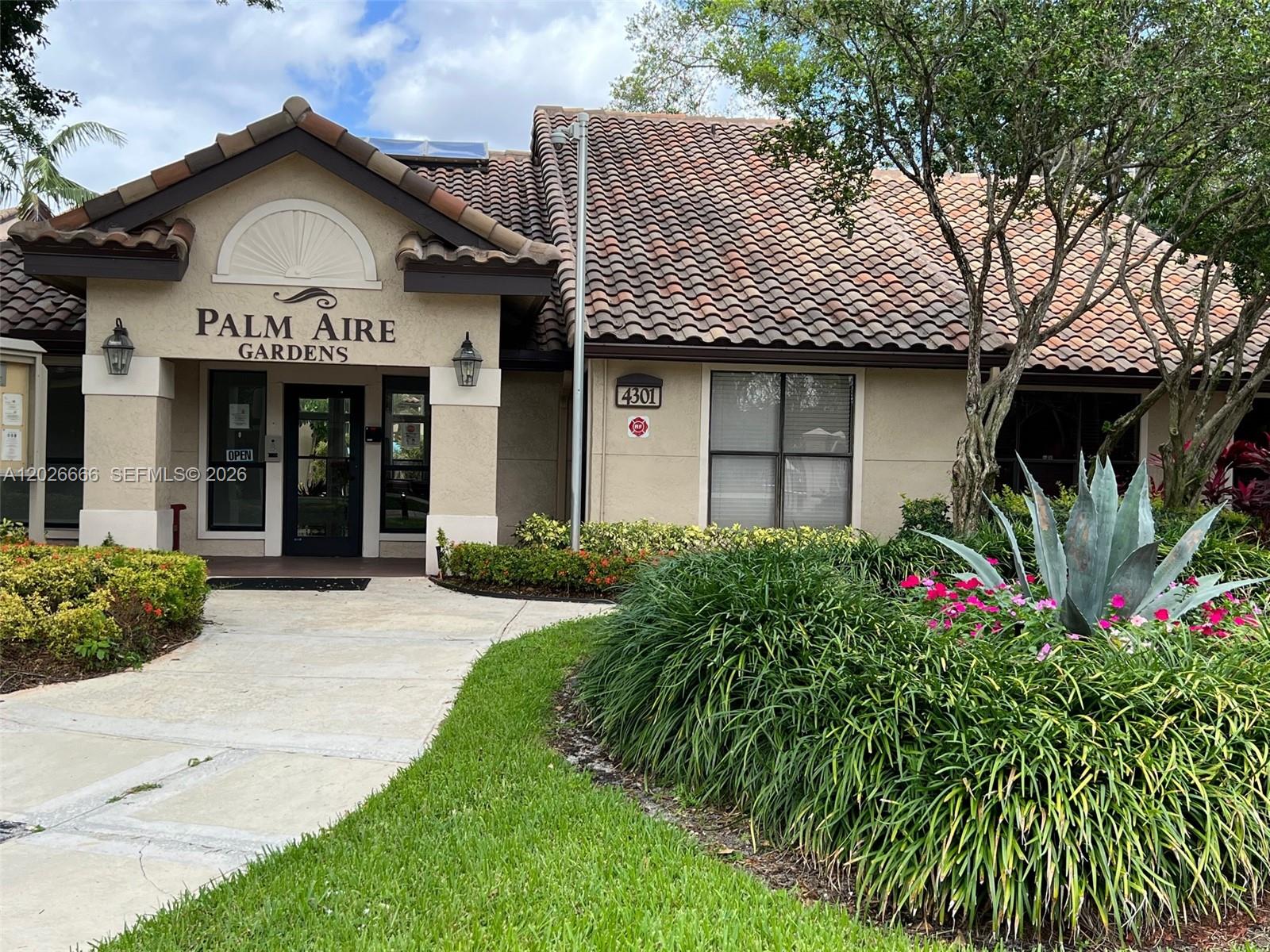 The exterior of a beige building with a tiled roof and a landscaped front yard — 4581 W Mcnab Rd # 20, Pompano Beach FL 33069, POMPANO BEACH, FL