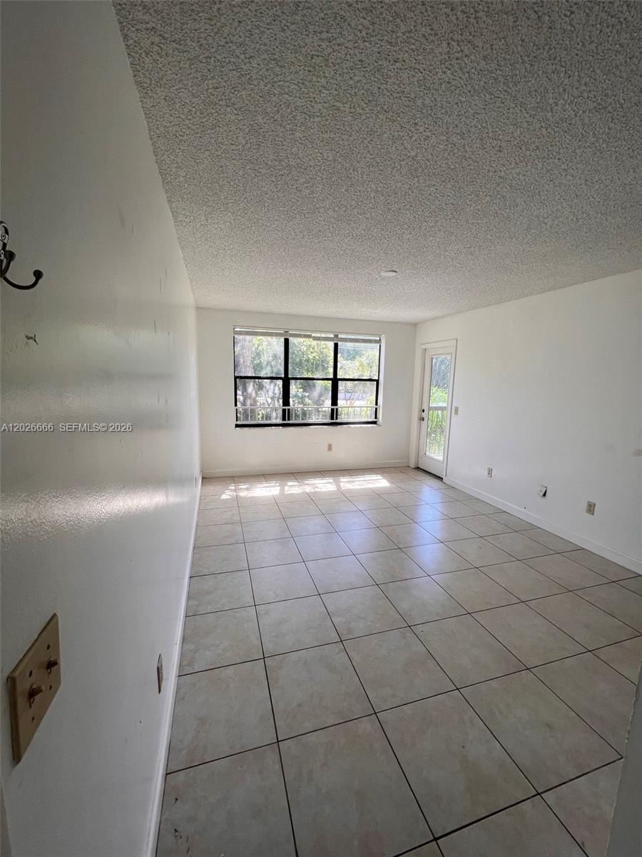 An empty room features white walls, a popcorn ceiling, and light-colored square floor tiles — 4581 W Mcnab Rd # 20, Pompano Beach FL 33069, POMPANO BEACH, FL