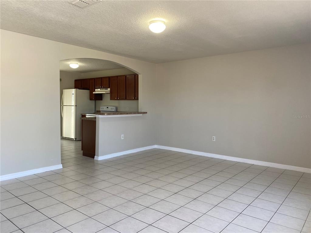 An open-concept living area with tiled floors leads to a kitchen with dark wood cabinets — 1830 2ND STREET NW UNIT B, WINTER HAVEN, FL