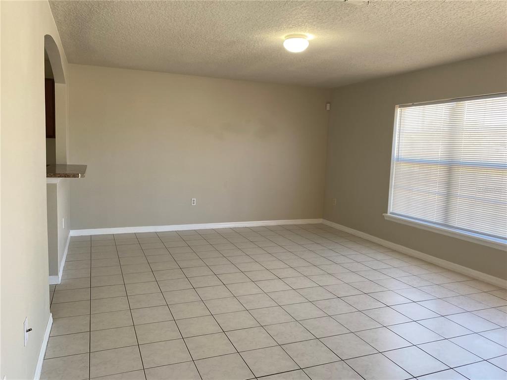 An empty room with beige walls, tile flooring, and a window with blinds — 1830 2ND STREET NW UNIT B, WINTER HAVEN, FL