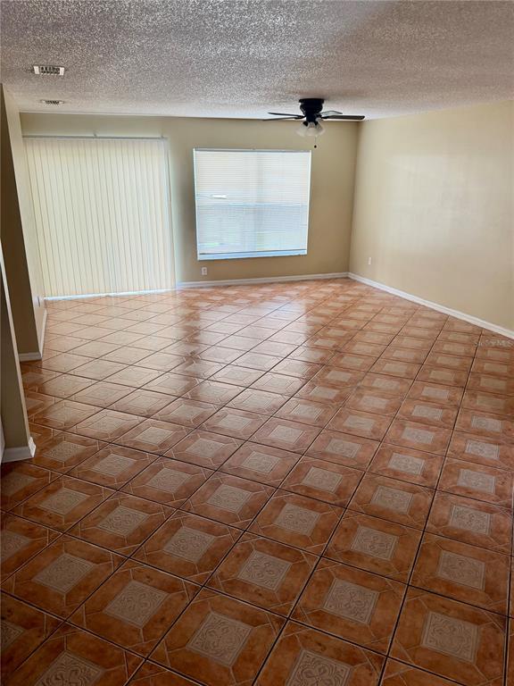 An empty room features tan tile flooring, a ceiling fan, and a sliding glass door — 1326 AGUACATE COURT, ORLANDO, FL