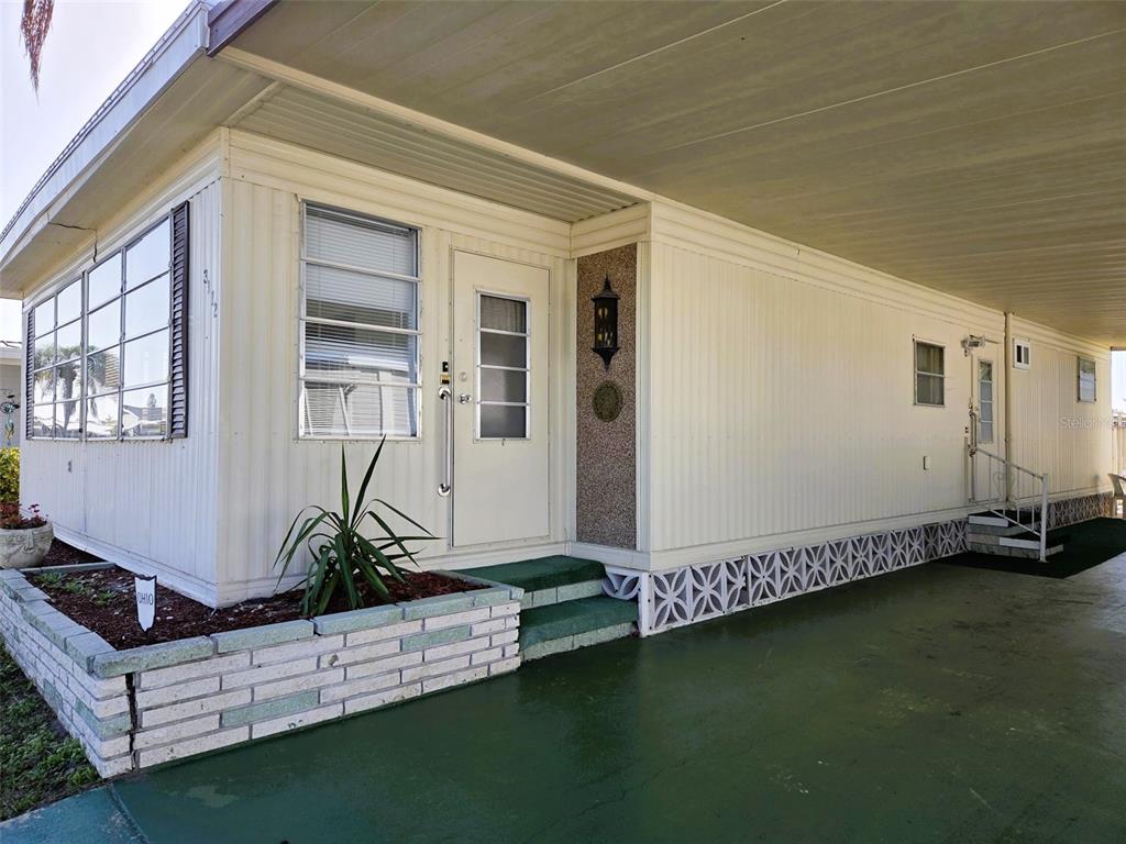 The exterior of a mobile home features a carport, a small porch, and white siding — 3312 OVERCUP OAK TERRACE, SARASOTA, FL