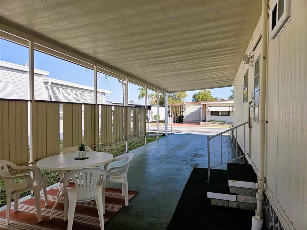 A covered outdoor patio with a dining set, concrete flooring, and steps leading to a home — 3312 OVERCUP OAK TERRACE, SARASOTA, FL