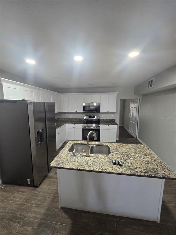 A kitchen features white cabinetry, granite countertops, stainless steel appliances, and a central island — 3905 E OSBORNE AVENUE, TAMPA, FL