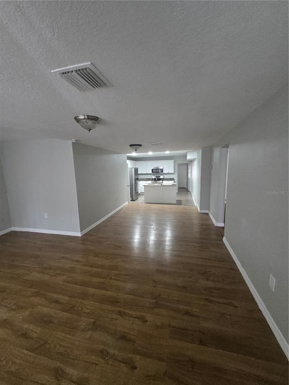 An open-concept living area with wood-look flooring leads to a kitchen with white cabinets — 3905 E OSBORNE AVENUE, TAMPA, FL