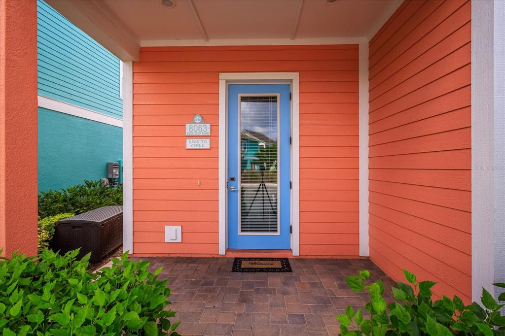 A bright blue front door is centered on a peach-colored exterior wall with horizontal siding — 8063 KNEE DEEP ROAD, KISSIMMEE, FL