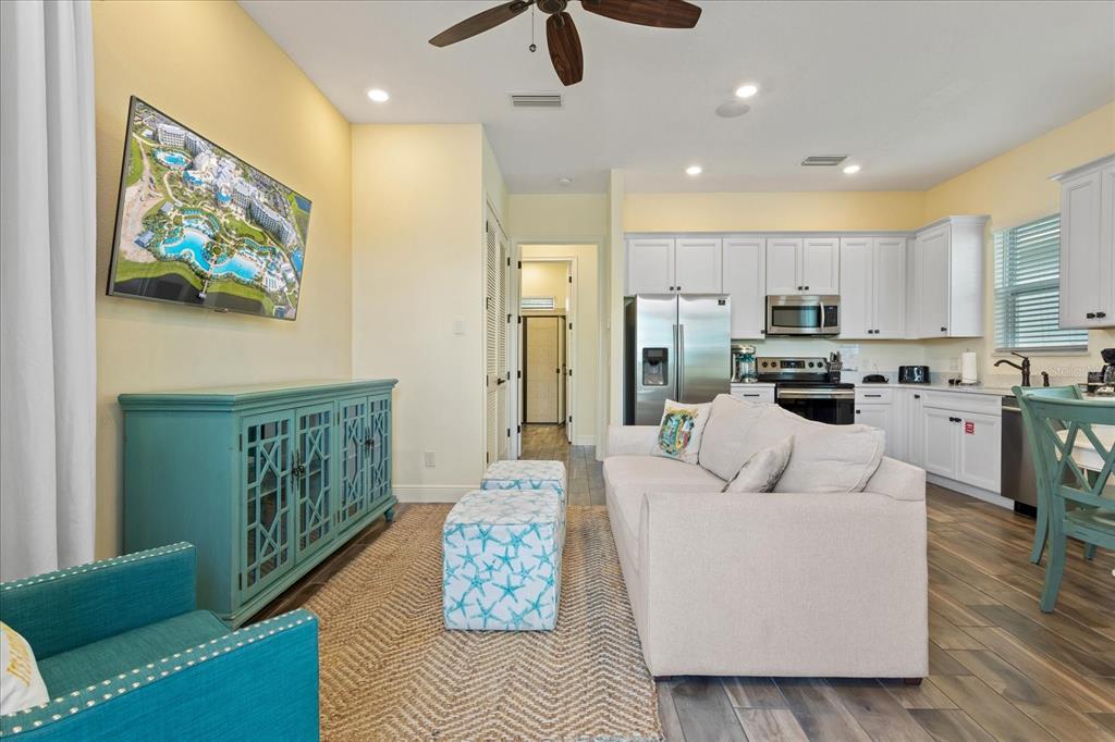 A living room with a teal cabinet, beige sofa, and open kitchen with white cabinets — 8063 KNEE DEEP ROAD, KISSIMMEE, FL