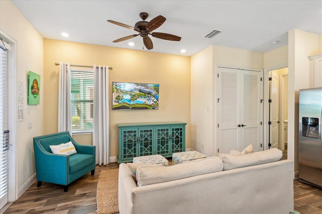 A living room features a beige sofa, a teal armchair, a media console, and a television — 8063 KNEE DEEP ROAD, KISSIMMEE, FL