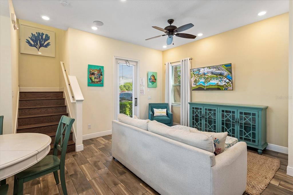 A living room with a sofa, teal console, staircase, and light yellow walls — 8063 KNEE DEEP ROAD, KISSIMMEE, FL