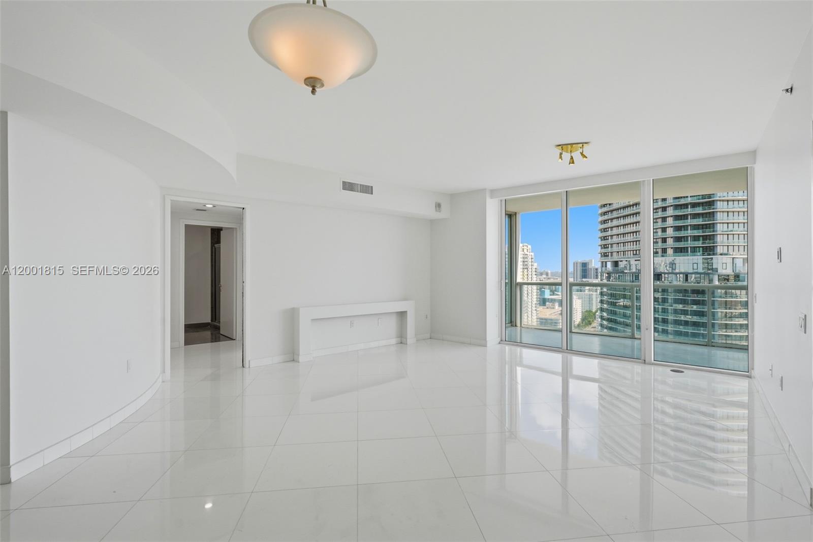 A bright, empty living room features white tile floors, a ceiling light, and floor-to-ceiling windows — 450 Alton Rd # 2704, Miami Beach FL 33139, MIAMI BEACH, FL