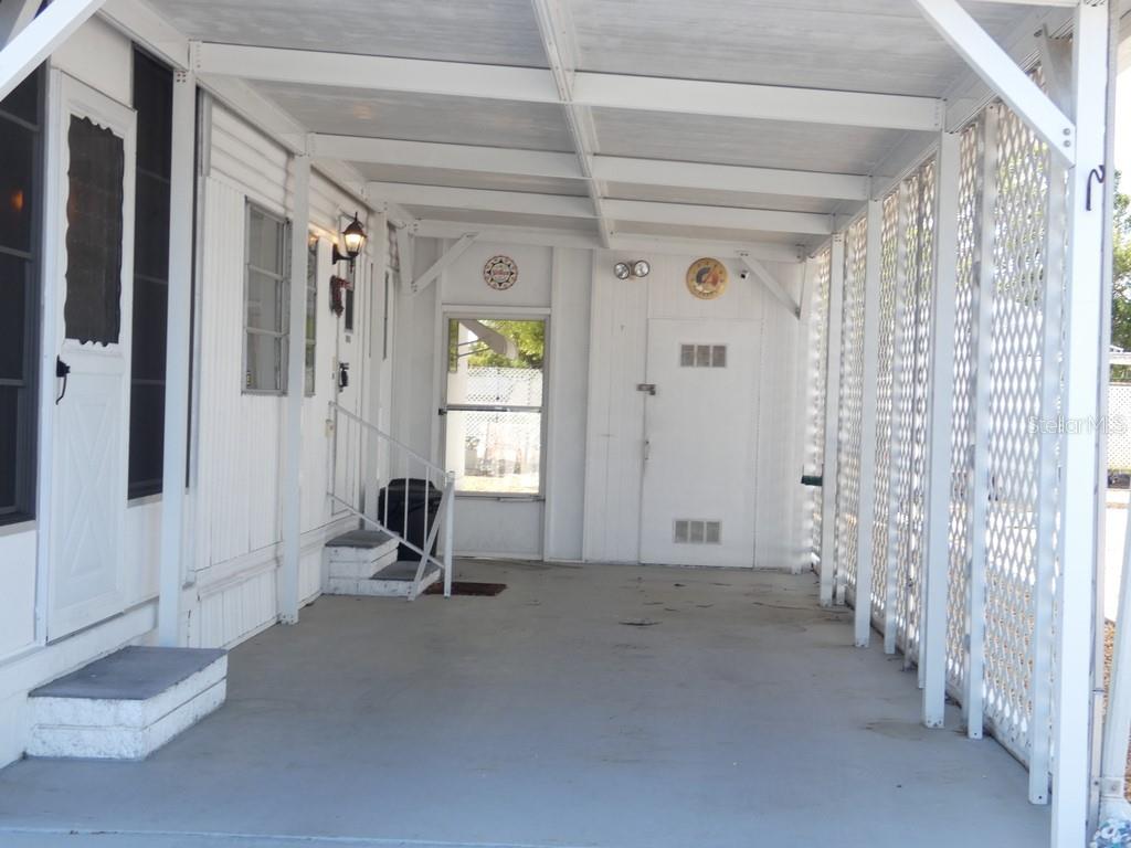 A covered carport with white siding, a concrete floor, and a lattice privacy screen — 3612 TIKI DRIVE, HOLIDAY, FL