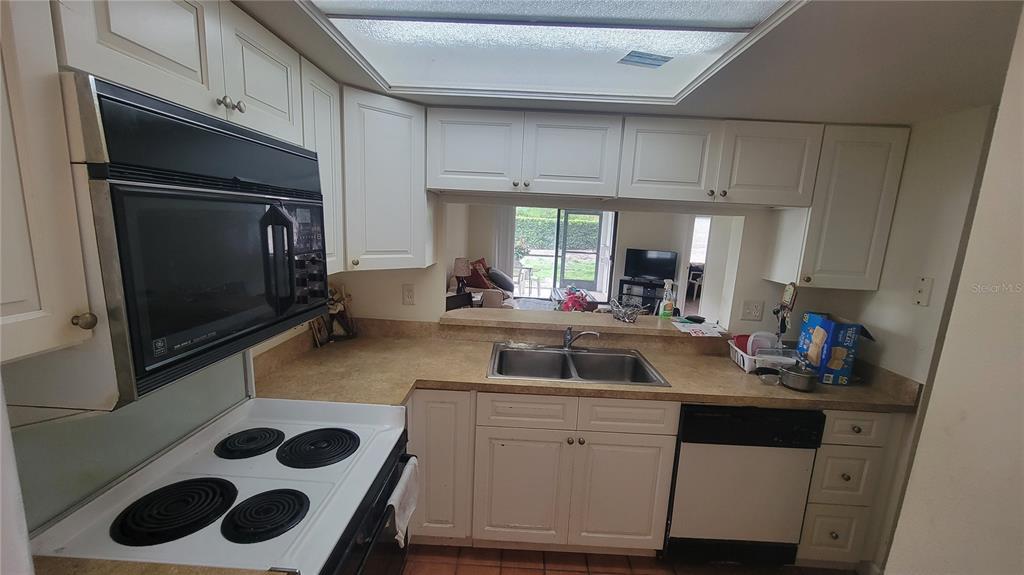 A kitchen with white cabinets, a double sink, and a black stove and dishwasher — 2737 E ENTERPRISE ROAD UNIT 151, CLEARWATER, FL