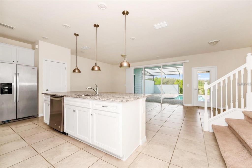 A kitchen with a granite-topped island, stainless steel appliances, and a view of a pool — 7513 OAK SPRING LANE, DAVENPORT, FL