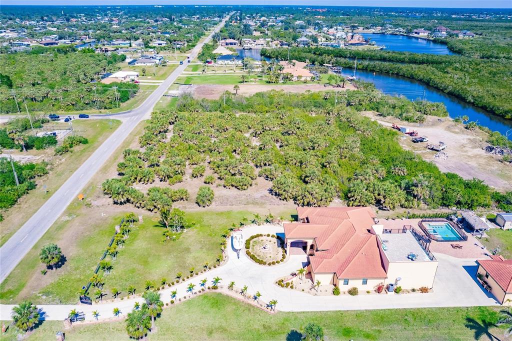 An aerial view shows a house with a pool and circular driveway on a large lot — 19155 MIDWAY BOULEVARD, PORT CHARLOTTE, FL